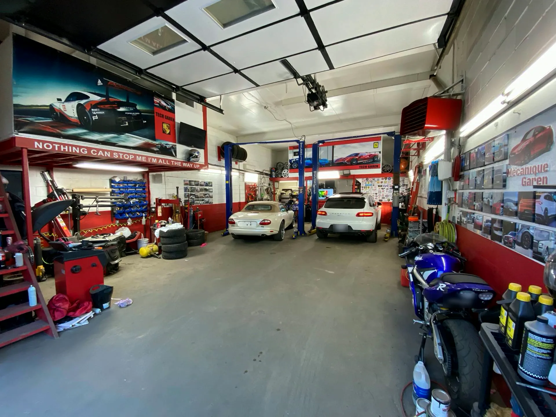 L'intérieur du garage: lifts bleus, murs rouges, voitures européennes