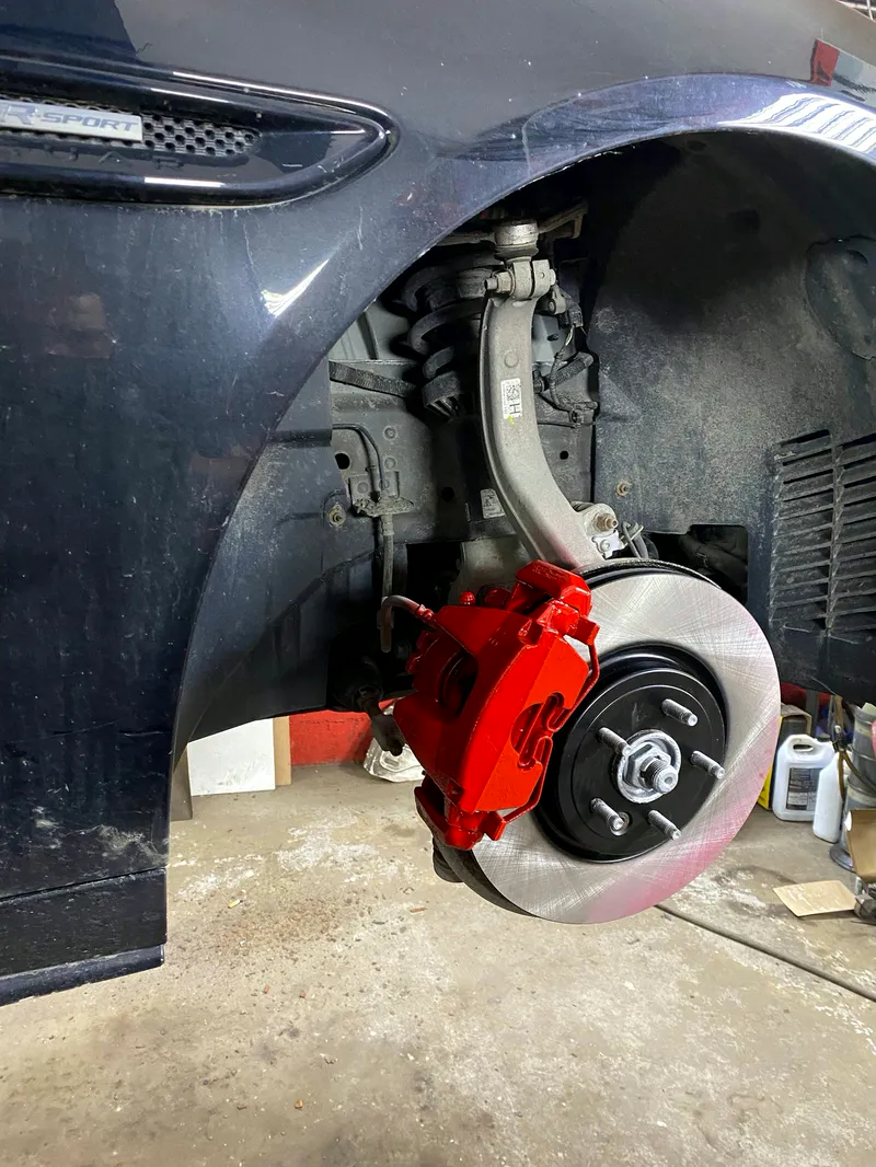 Étrier rouge et disque neuf installés dans le garage